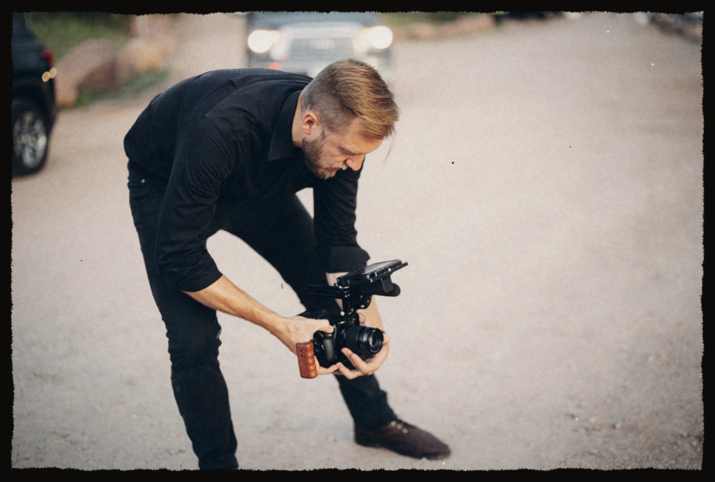 Luke crouched low with a cinema camera on a gravel road
