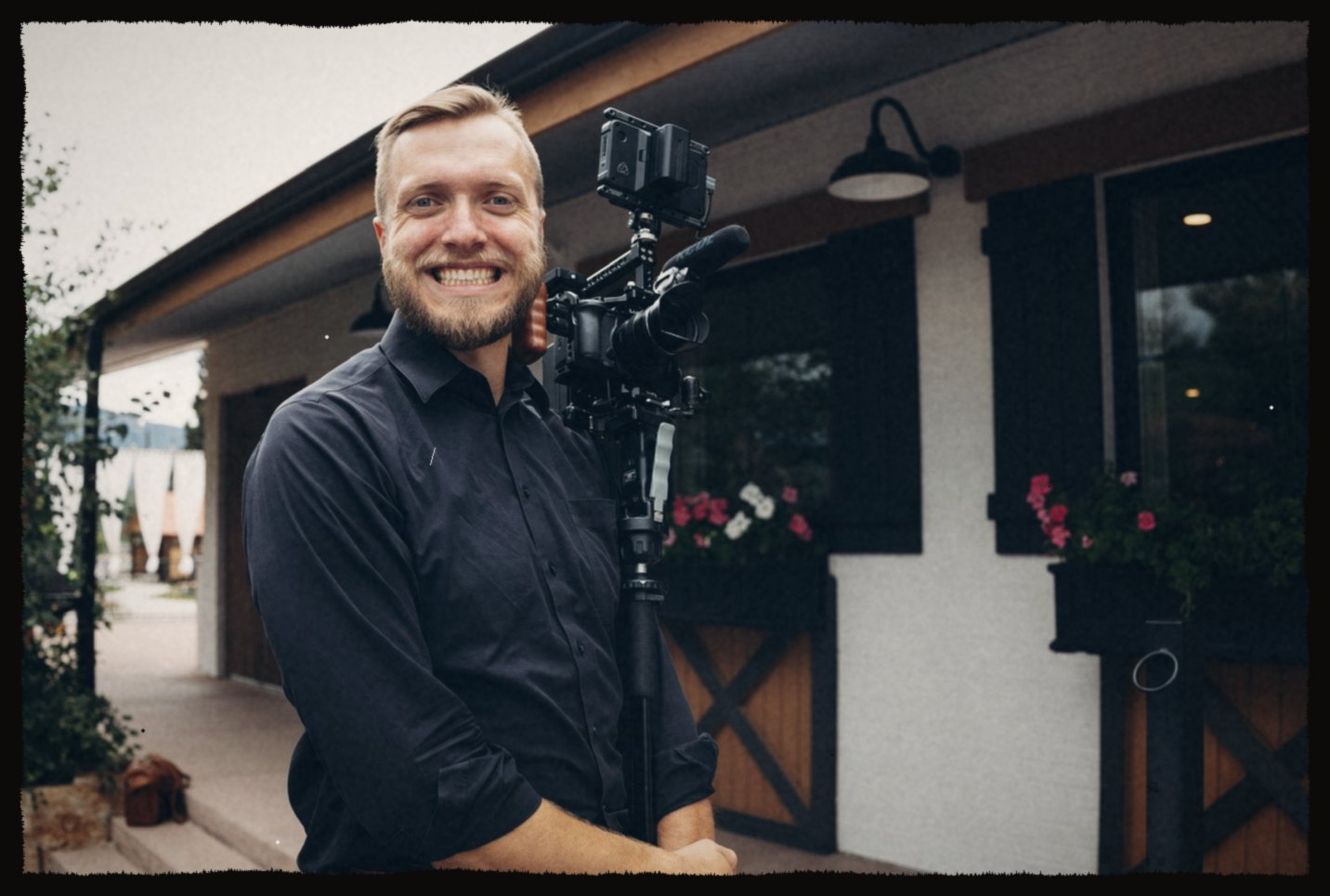 Luke smiling beside a rigged cinema camera on a monopod