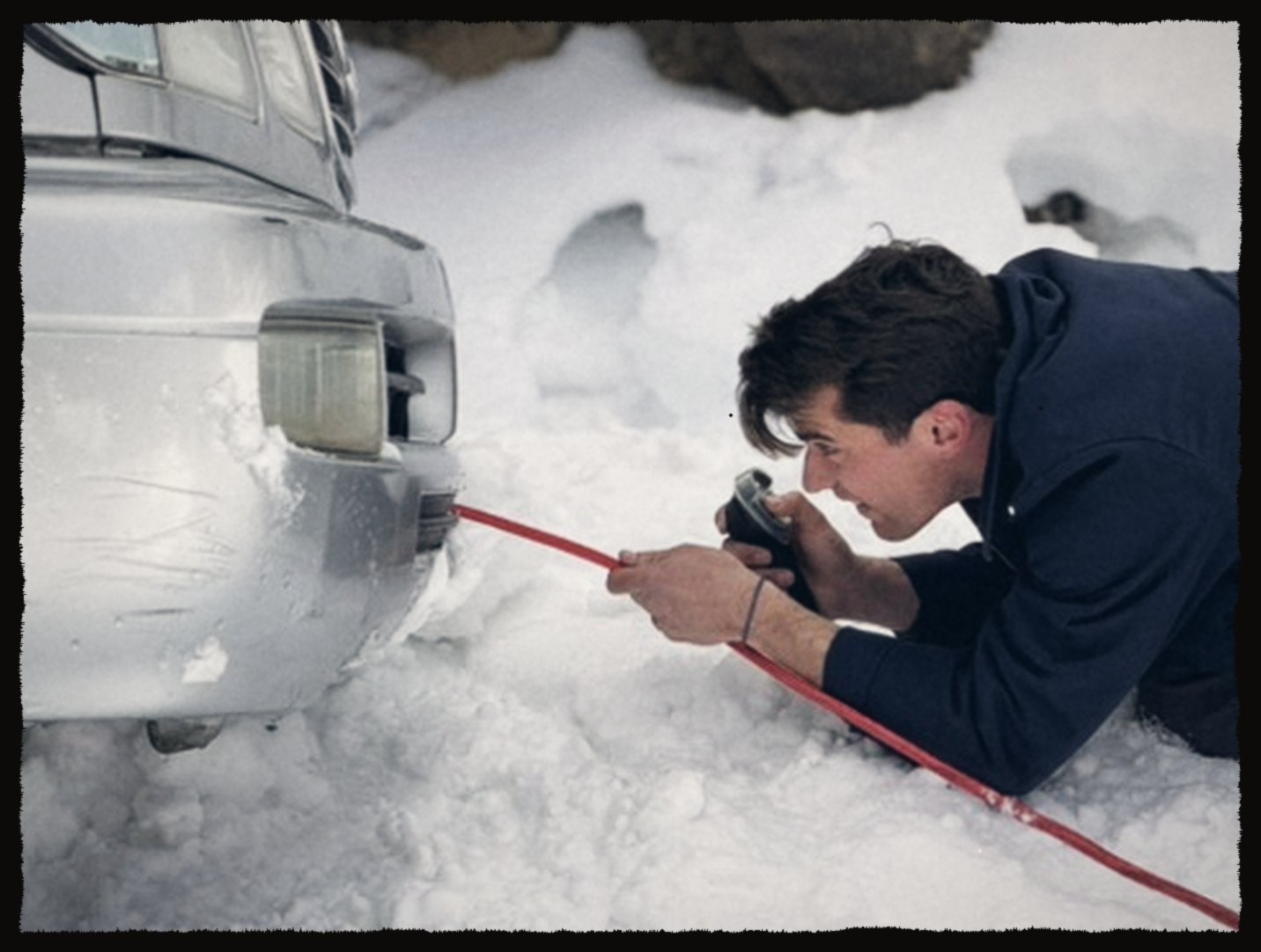 Crouching in the snow to film a tow strap on an SUV bumper